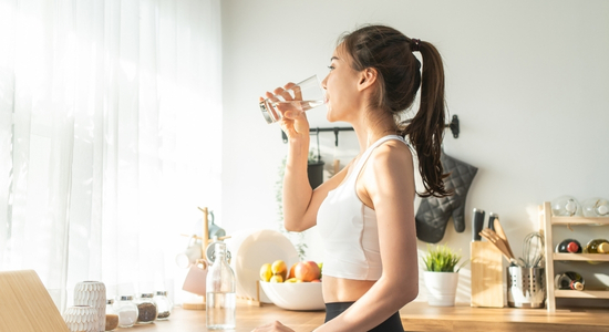 Eine Frau drinkt einen Smoothie in der Küche